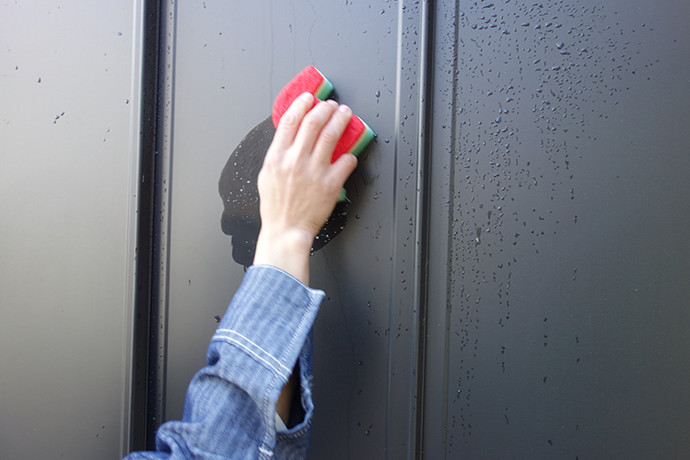 ゼロキューブ(ZERO-CUBE)のガルバリム鋼板の外壁を中性洗剤を含んだスポンジで洗っている様子